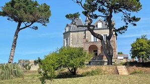 Een groot, historisch gebouw met een opvallende, gebogen entree en een steil dak.
