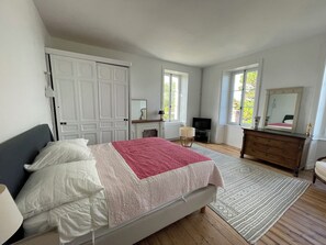 A bedroom with a bed, dresser, TV, and a large window. - Ideal for 2 families, large charming house, sea view, direct access to the beach (Saint-Jacut-de-la-Mer)