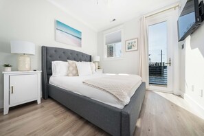 Une chambre à coucher avec un lit, des tables de chevet, une télévision et une vue par la fenêtre.