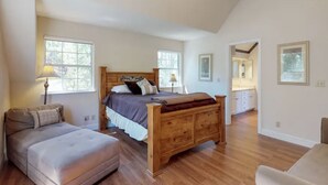 A bedroom with a wooden bed, a nightstand, a lamp, and a view of the bathroom.