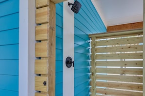 Un cancello in legno con una chiusura metallica, una recinzione in legno e un muro blu e bianco con una porta in legno.