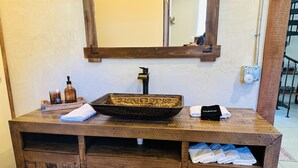A wooden vanity with a large mirror, a vessel sink, and storage cabinets. - Red Barn in Wine Country (Jacksonville)