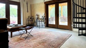 A spacious room with a large window, a dining table with chairs, a sofa, and a staircase. - Red Barn in Wine Country (Jacksonville)