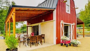 A red barn with a covered patio area, a dining table, and chairs. - Red Barn in Wine Country (Jacksonville)