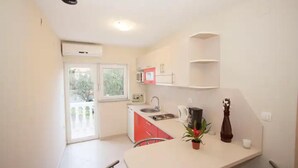 A compact kitchen with a window, a sink, a coffee maker, and a potted plant. - Two bedroom apartment for 4 person (Jadranovo)