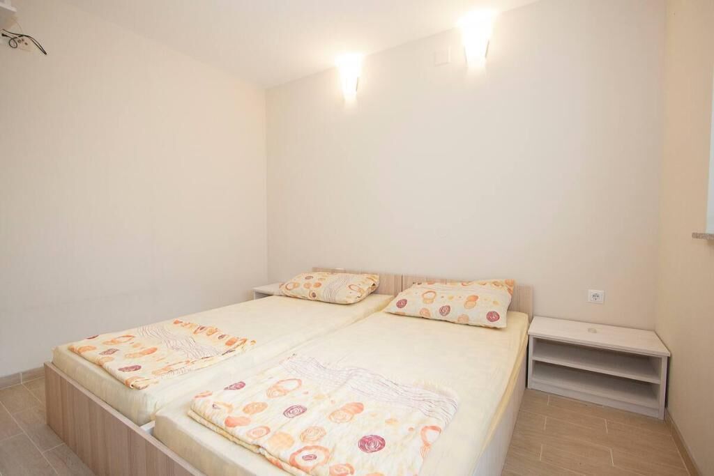 Un dormitorio con dos camas, cada una con una colcha estampada y almohadas a juego. Hay una mesita de noche pequeña a la derecha de las camas.