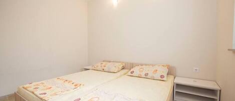 Un dormitorio con dos camas, cada una con una colcha estampada y almohadas a juego. Hay una mesita de noche pequeña a la derecha de las camas.
