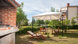 A patio with a covered seating area, a barbecue grill, and a brick wall. - Two bedroom apartment for 4 person (Jadranovo)