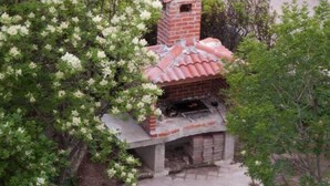 A brick structure with a red-tiled roof, possibly a small building or shed, surrounded by greenery. - Two bedroom apartment for 4 person (Jadranovo)