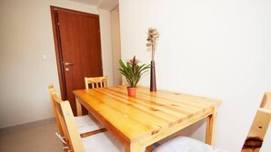 Una mesa de madera para comer con cuatro sillas, una planta en maceta y un florero con flores secas.