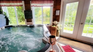 Ein Whirlpool mit einem Weinglas, eine Tafel mit Schrift und Blick auf Grünfläche im Freien.