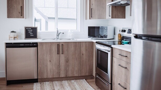 Eine moderne Küche mit Holzschränken, Edelstahlgeräten und einer eingebauten Mikrowelle.