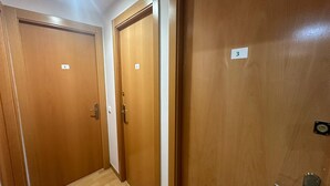 Ein Flur mit drei Holztüren, jede mit einer Nummer beschriftet.