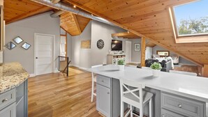 Una cocina amplia con una isla grande, vigas de techo de madera y un tragaluz.