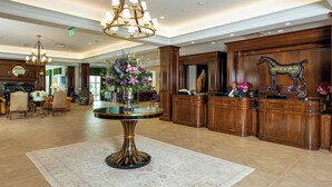 A lobby with a round table, wooden reception desk, and a chandelier.