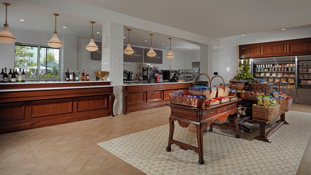 A spacious kitchen with a large island, wooden cabinets, and a variety of food items displayed on the counter.