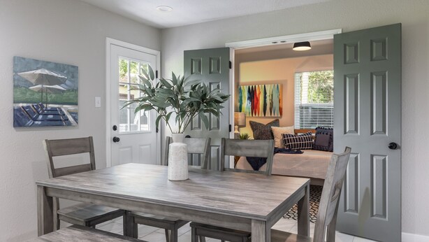 A dining area with a wooden table and chairs, a potted plant, and a painting on the wall. - Bright and Stylish Home (Dallas)
