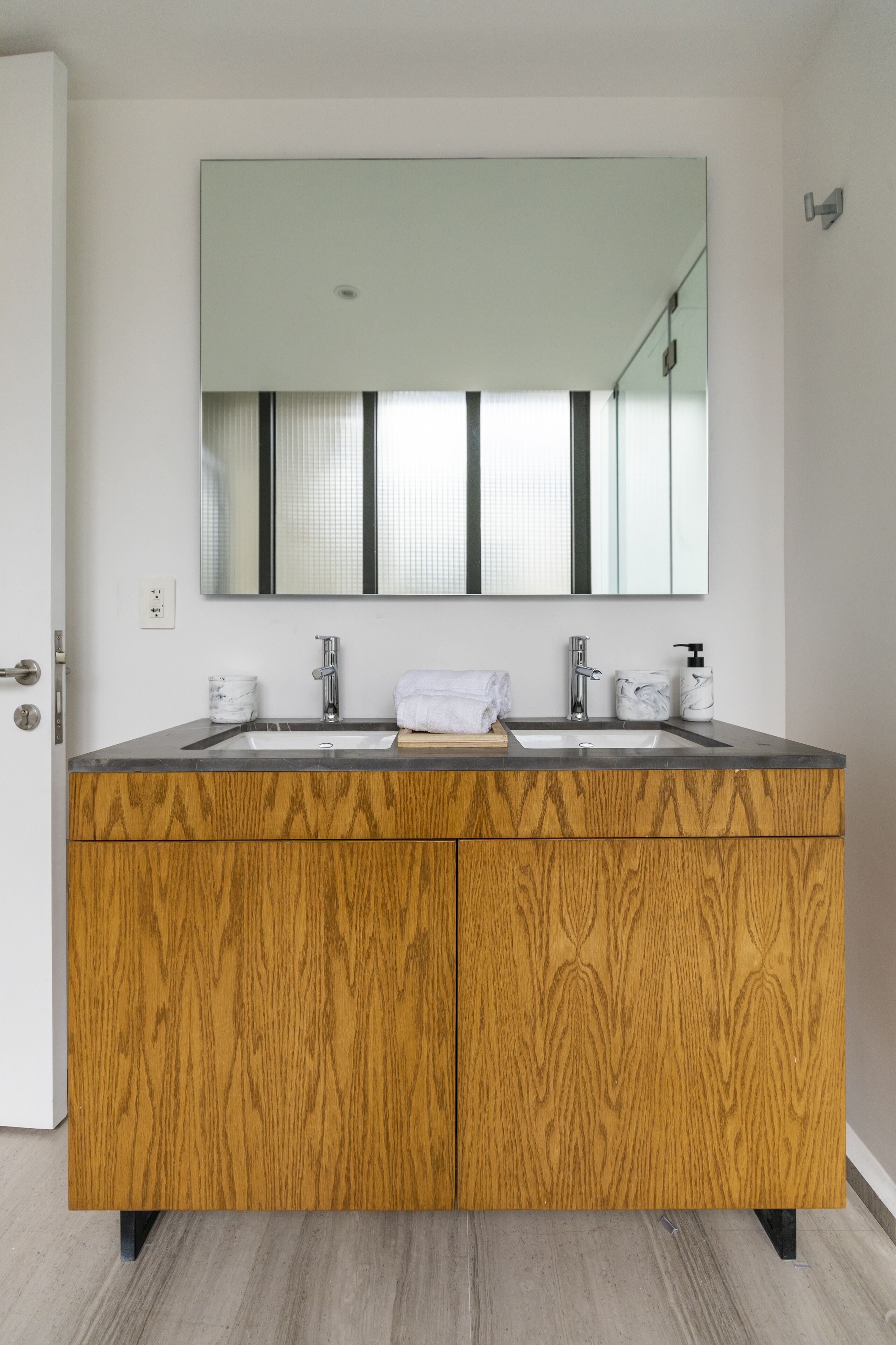 Ein modernes Badezimmer mit einem Holzbidet, zwei Waschbecken und einem großen Spiegel.