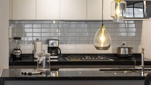 Une cuisine moderne avec un plan de travail noir, une cuisinière, un four à micro-ondes et des luminaires suspendus.