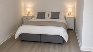 Un dormitorio con cama, dos mesitas de noche y dos lámparas.