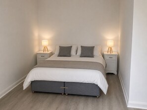 A bedroom with a bed, two bedside tables, and two lamps.