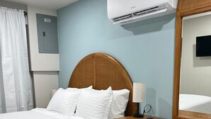 Ein Hotelzimmer mit einem Bett, einem Holzschrank und einer Klimaanlage.