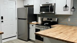 Eine moderne Küche mit weißen Schränken, Edelstahlgeräten, einer Holz Arbeitsplatte und zwei Barhocker.