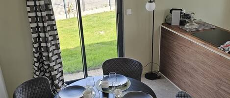 A dining area with a round table set for six, surrounded by six cushioned chairs.