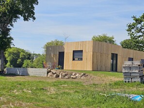 Een modern houten gebouw met een plat dak, een klein raam en een deur.