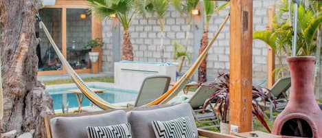 Un espacio al aire libre con muebles de madera, que incluye un sofá, sillas, una mesa y una hamaca.