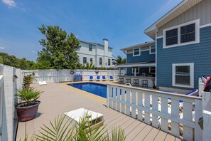 A pool area with a wooden deck, lounge chairs, and a white fence. - 4 Play- 5 Bd., Dog Friendly, Game Rm., Private Pool, Easy Bch Access (Virginia Beach)