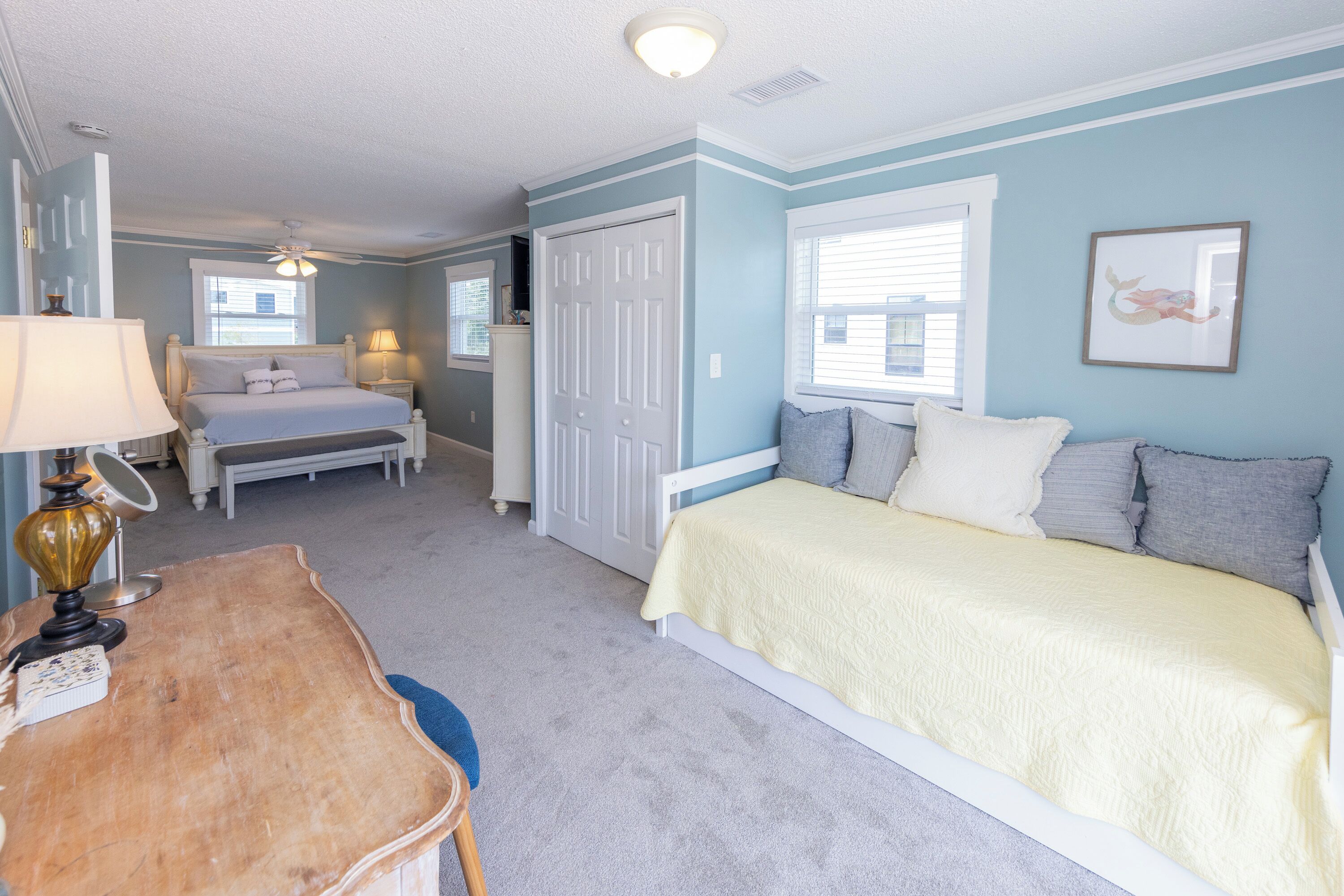 A bedroom with a bed, bedside table, lamp, and a dresser.