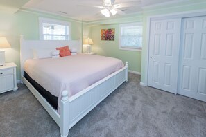A bedroom with a bed, nightstands, a ceiling fan, a door, and a window.