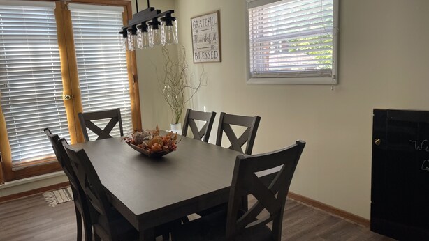 Un coin repas avec une table et des chaises en bois, un bol décoratif et un panneau fixé au mur.