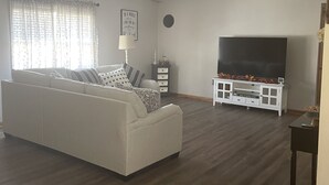 Un salon avec un canapé blanc, un téléviseur à écran plat et un plancher en bois.