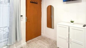 Ein Flur mit einer Holztür, einem weißen Schrank, einem an der Wand befestigten Netflix-Schild und einem kleinen Topfpflanzen.