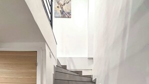 Eine moderne Treppe mit einer Holztür am Fuß und einem Wandbild darüber.