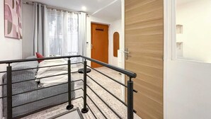Ein modernes Hotelzimmer mit einem Bett, einer Holztür und einer Treppe mit Metallgeländer.