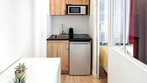 Een kleine keuken met houten kastjes, een magnetron, een spoelbak en een vaatwasser.