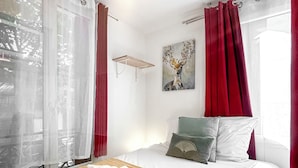 Een hotelkamer met een bed, een schilderij, een raam met gordijnen en een handdoek op het bed.