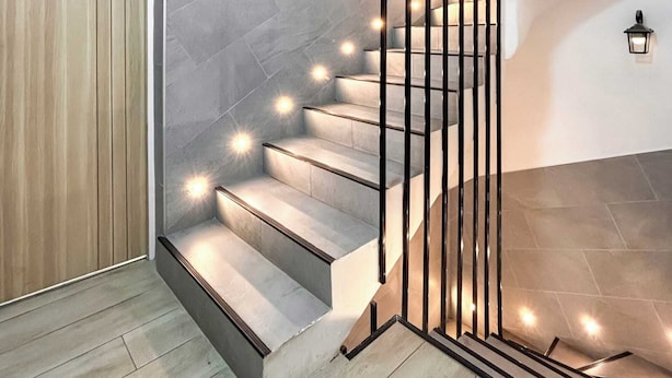 Een moderne trap met een houten deur en een lamp aan de muur.