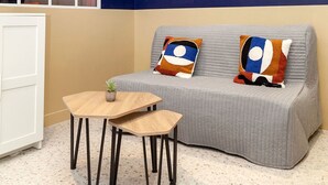 A modern room with a grey sofa, two matching pillows, a small wooden table, and a large abstract painting on the wall. - David D Angers 53 - One Bedroom Apartment, Sleeps 4 (Paris)