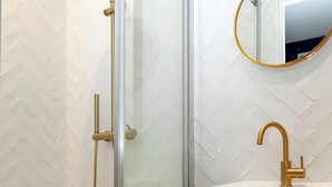 A modern bathroom with a glass-enclosed shower, a white sink with a gold faucet, and a wooden cabinet. - David D Angers 53 - One Bedroom Apartment, Sleeps 4 (Paris)
