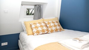 Un dormitorio con cama, almohadas, una ventana y vistas a zonas verdes.
