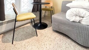 A hotel room with a bed, a small table, two chairs, a window with curtains, and a large circular artwork on the wall. - David D Angers 42 - One Bedroom Apartment, Sleeps 3 (Paris)