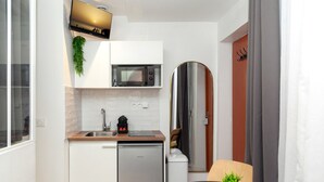 A compact kitchen with a microwave, sink, and dishwasher. There is a small table with a plant and a remote control. - David D Angers 42 - One Bedroom Apartment, Sleeps 3 (Paris)