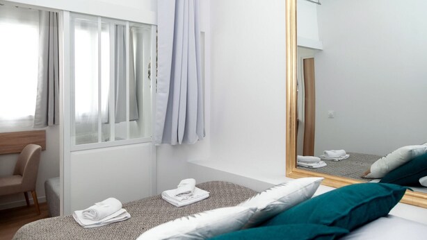 A hotel room with a bed, a chair, a window with curtains, and a mirror. - David D Angers 29 - One Bedroom Apartment, Sleeps 3 (Paris)