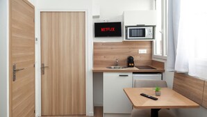A compact kitchenette with a microwave, a coffee maker, and a sink. A television displaying 'NETFLIX' is mounted above the counter. - David D Angers 29 - One Bedroom Apartment, Sleeps 3 (Paris)