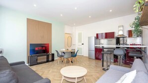 Un salon moderne avec un canapé, une petite table ronde et un téléviseur affichant le logo « NETFLIX ».
