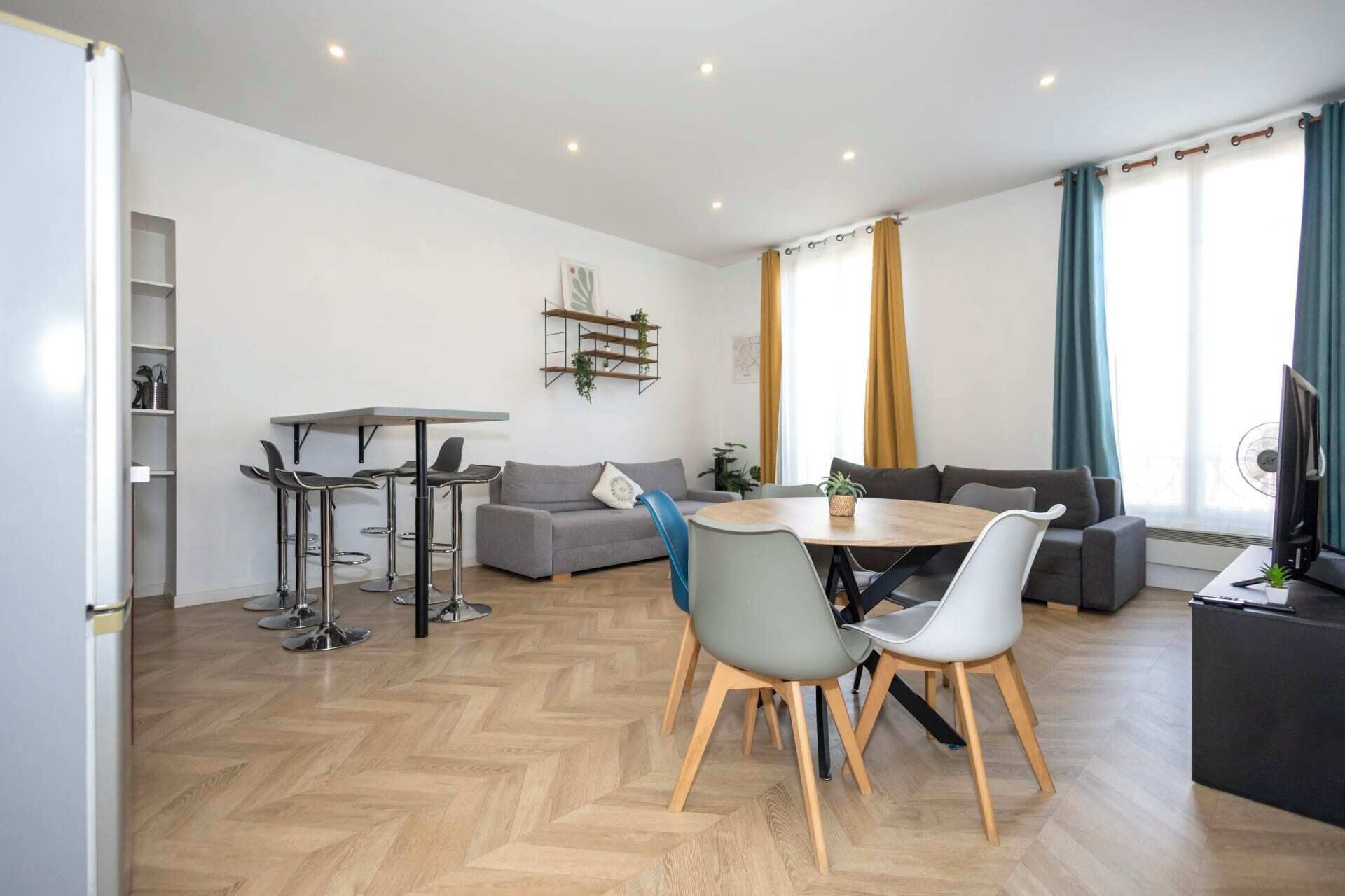 Een moderne woonkamer met een bank, een eettafel met stoelen, een televisie en een boekenkast.